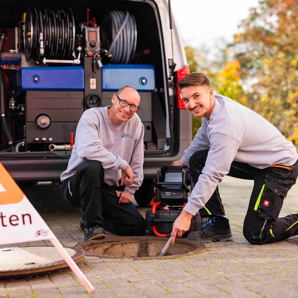 Zwei Techniker arbeiten mit der Kamera an einem geöffneten Schacht